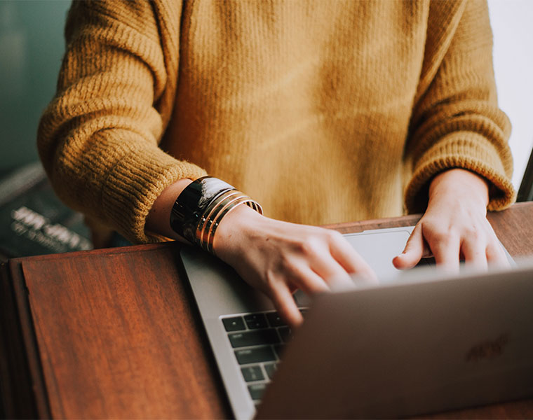 Close up of a person's torso and hands typing on a laptop